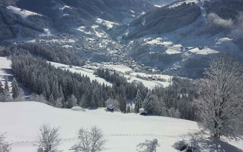 Verschneite Winterlandschaft mit Wald und Dorf in den Bergen, Natururlaub Familienurlaub Steffenegg